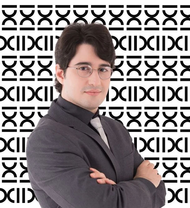 Advogado previdenciário especialista em planejamento previdenciário, trajando terno cinza escuro com gravata cinza claro, sobre o plano de fundo de padronagem com a logomarca do escritório. A fotografia tem moldura arredondada.